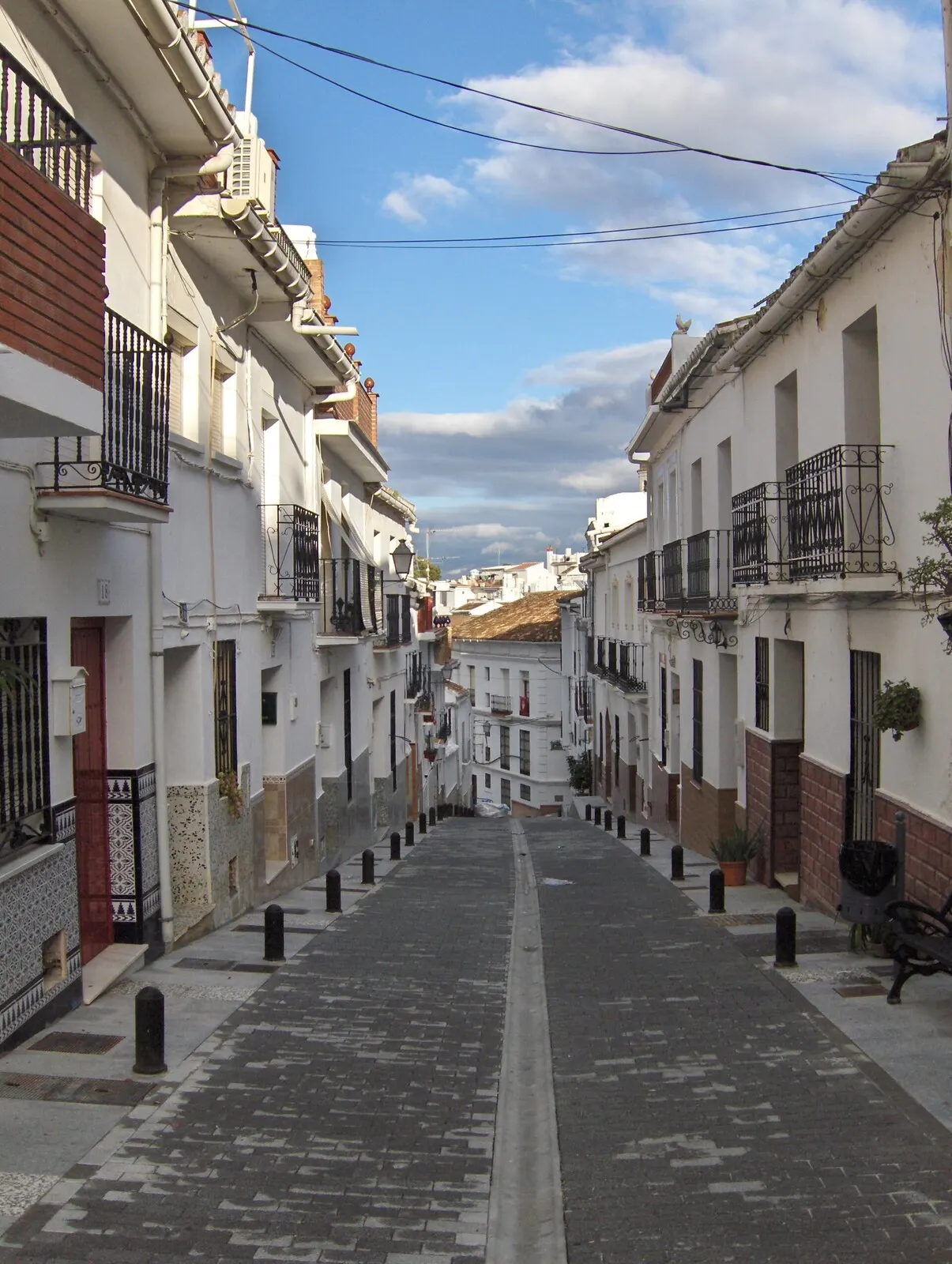Calle empedrada de casas encaladas con macetas