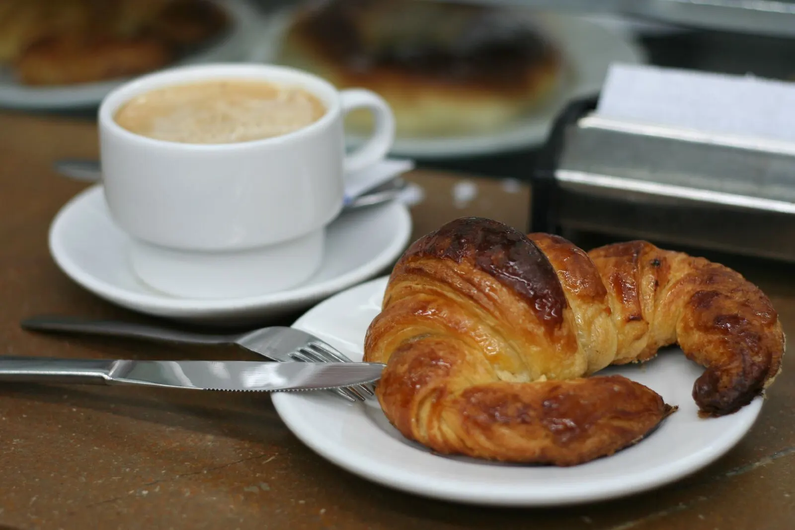 Café con leche y cruasán sobre una mesa de terraza