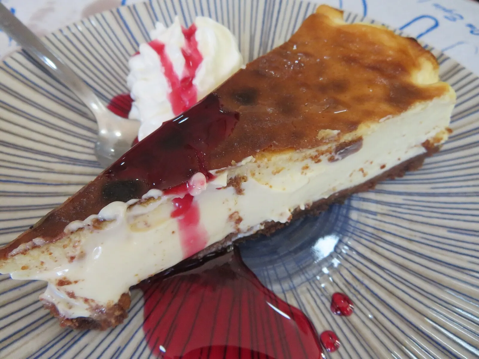 Porción de tarta de queso al horno con coulis de frutos rojos